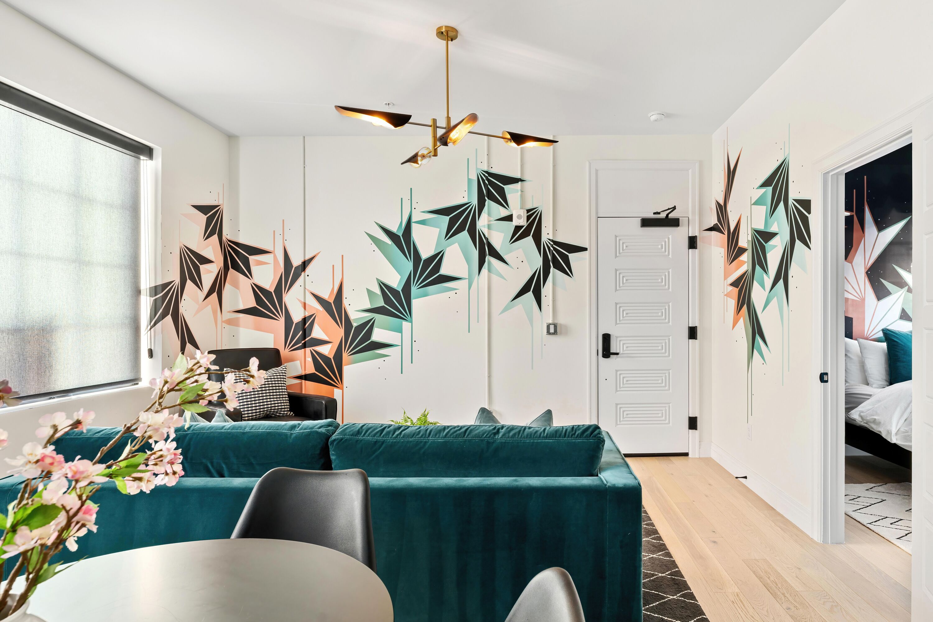 Un salon moderne avec des canapés de couleur turquoise, une table à manger et des œuvres d’art décoratives accrochées au mur.