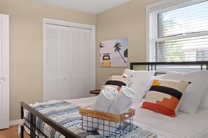 A bedroom with a bed, a wooden headboard, a bedside table, a nightstand, a window with blinds, a door, and a wall-mounted artwork. - * See the Beach from the Porch • Walk to Shore! (Lambton Shores)
