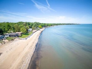 Una propiedad costera con playa de arena, una hilera de casas y un mar tranquilo.