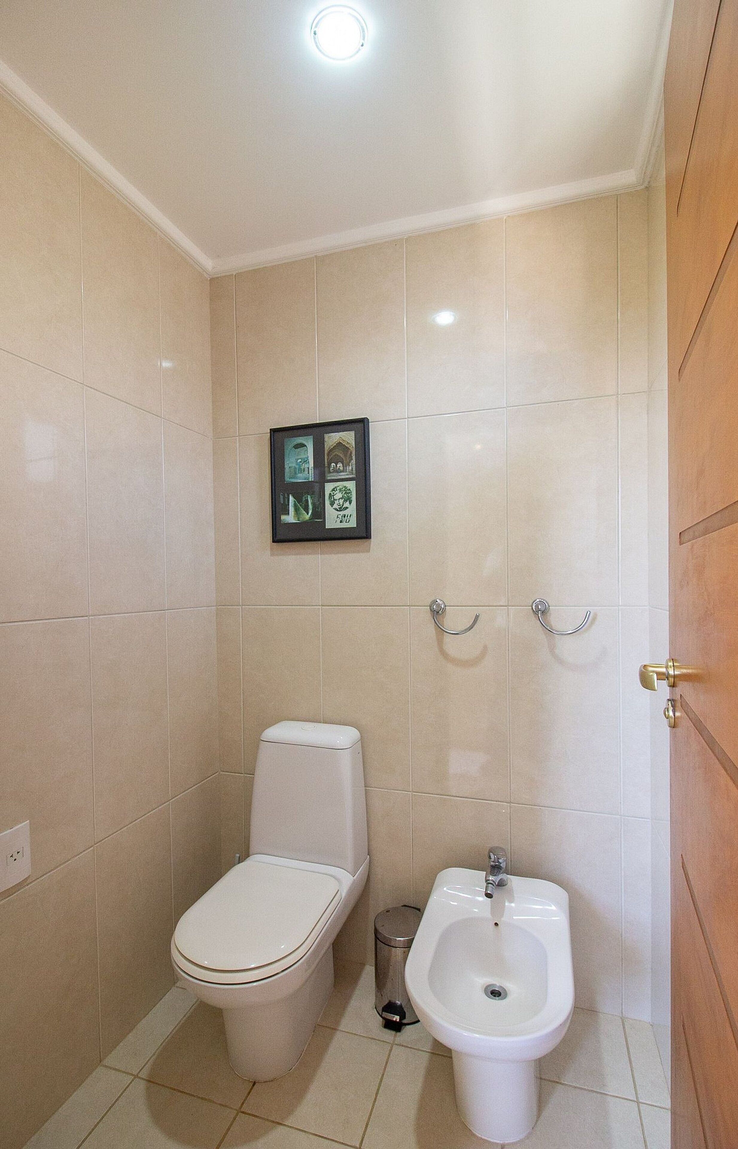 A small bathroom with a toilet, bidet, and a framed picture on the wall.
