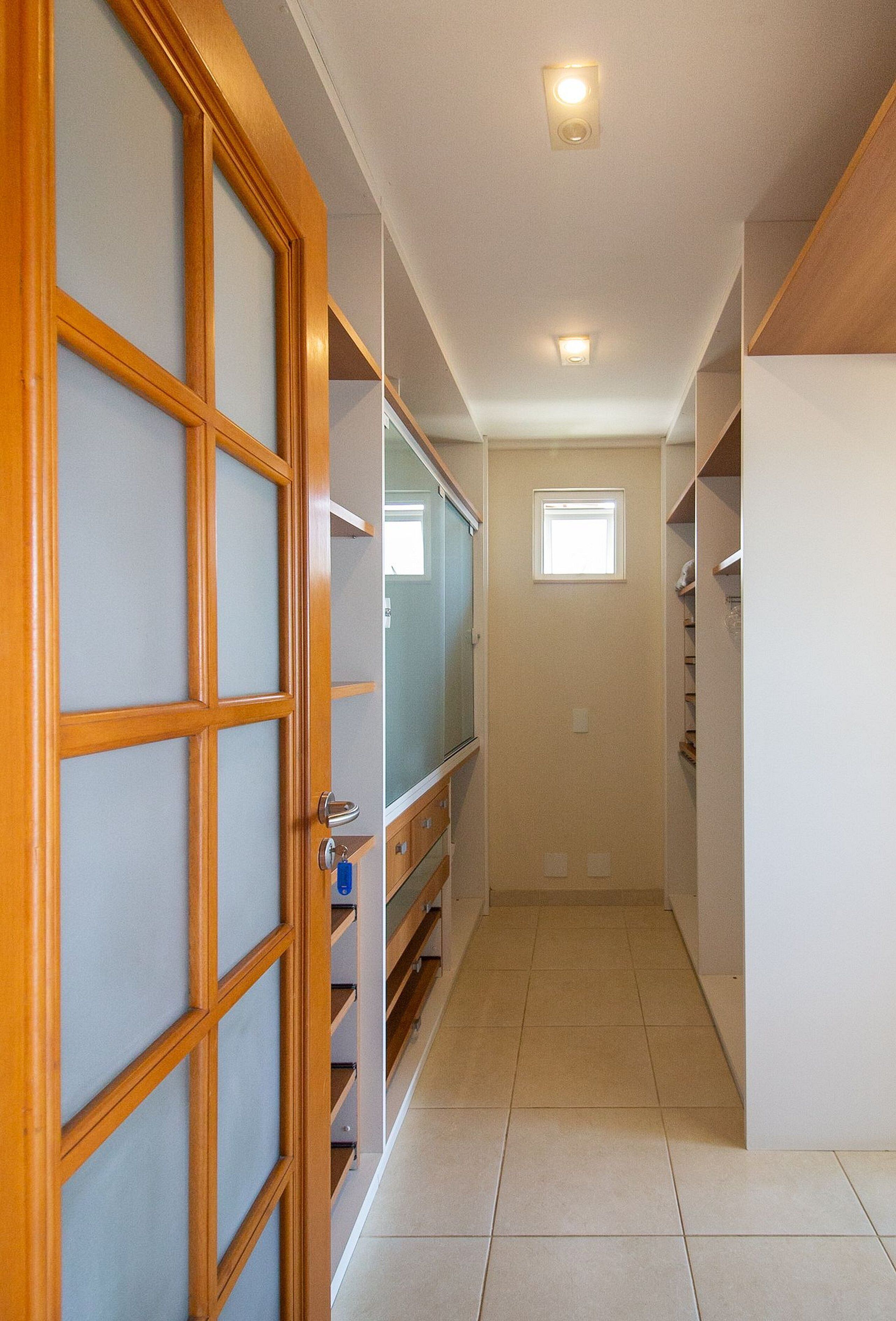 A narrow hallway with a wooden door, a small window, and built-in shelving.