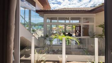 Una casa moderna con amplios ventanales, un balcón con plantas en macetas y vistas a la costa.