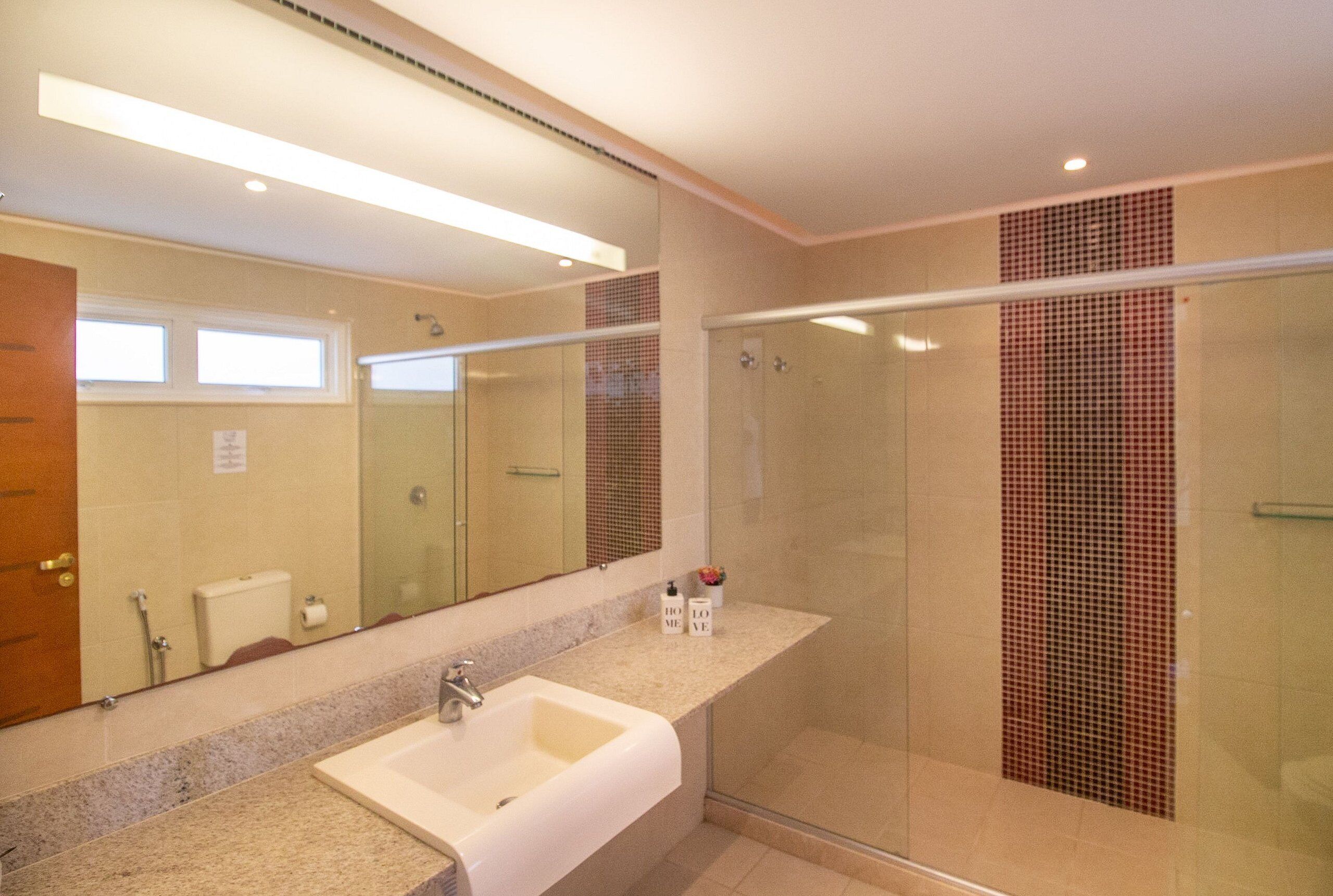 A modern bathroom with a large mirror, a bathtub, a glass shower enclosure, and a vanity with a sink.