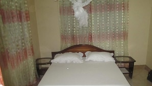 A bed with two pillows, a wooden headboard, and a glass table beside it. - Kinyaiya's Farm Lodge (Moshi)