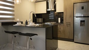 Una cocina moderna con una isla central, electrodomésticos de acero inoxidable y taburetes de bar.