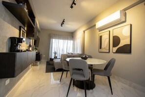 Een moderne woonkamer met een eethoek, met een zithoek, een koffieapparaat en kunstwerken aan de wanden.