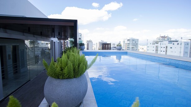 Una piscina en la azotea con un edificio moderno y cielo despejado.