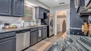 A modern kitchen with dark cabinets, stainless steel appliances, and a granite countertop. - Pool Playhouse: FirePit, Grill, Billiards & Jenga (Richardson)