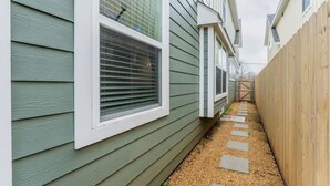 Um caminho estreito que leva a um edifício com revestimento verde e detalhes brancos.