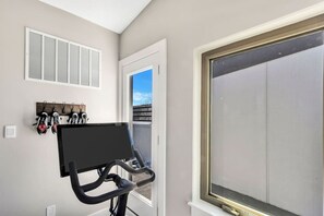 Une pièce équipée d’un vélo d’appartement, d’une fenêtre avec vue et d’un porte-chaussures fixé au mur.