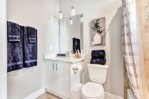 Une salle de bain équipée de toilettes, d’un lavabo, d’un miroir et de serviettes.