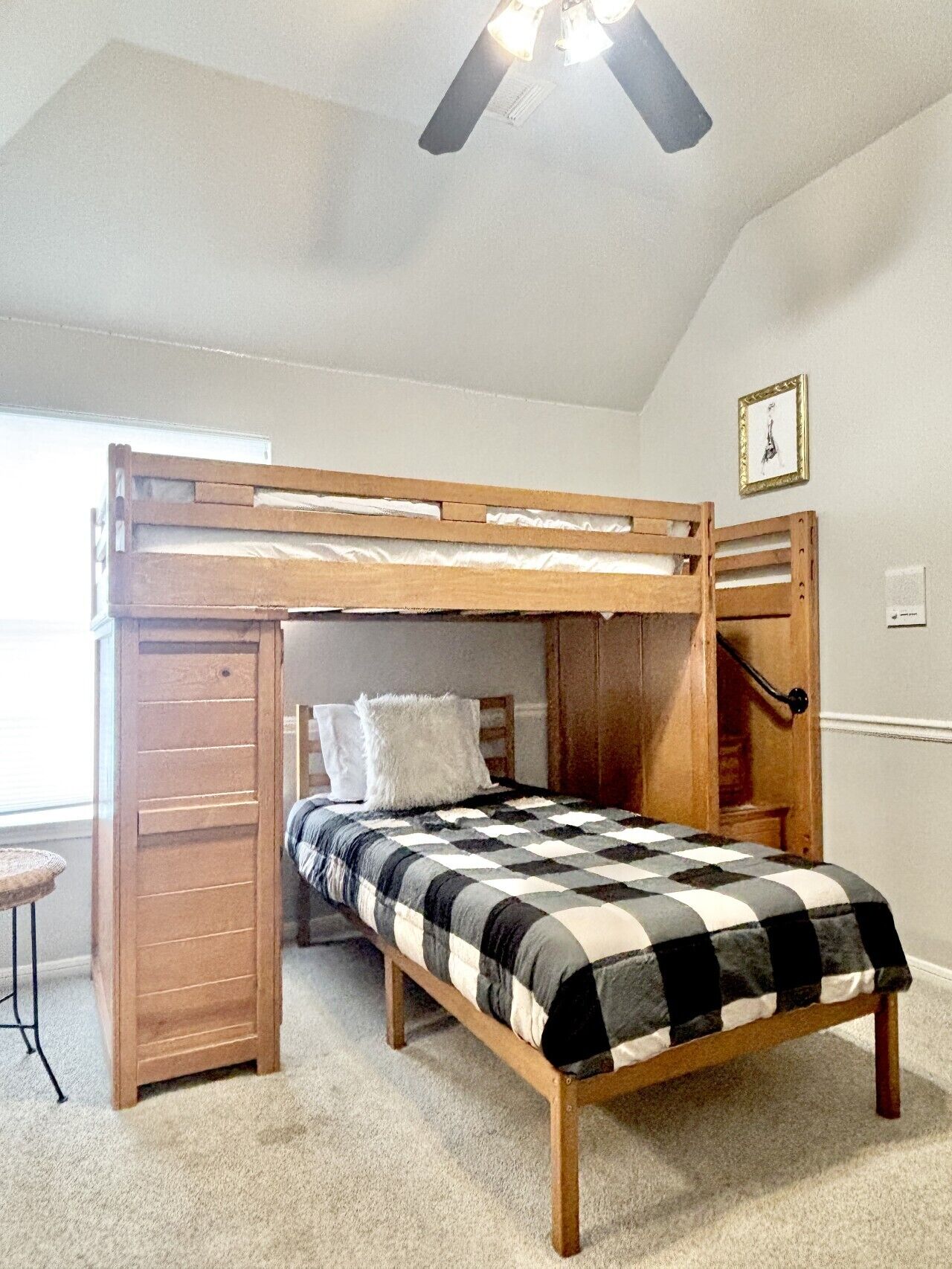 Una cama litera con estructura de madera y edredón a cuadros.