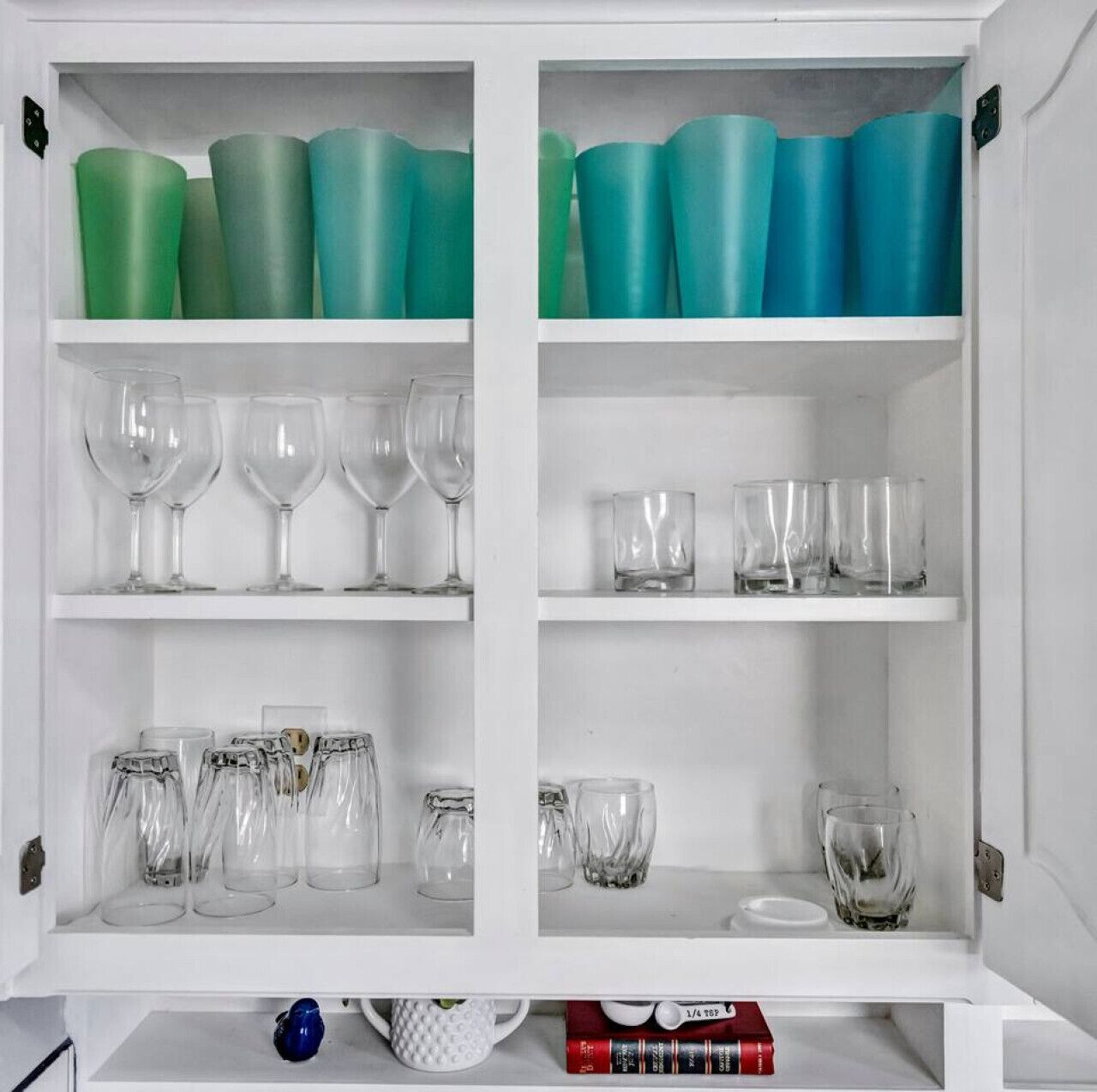 Ein Schrank mit Regalen, der verschiedene Gläser und Gefrierbecher beherbergt.