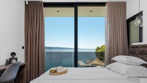 A hotel room with a bed, a desk, and a view of the sea. - Beachfront Villa Cordelia with Pool (Omiš)