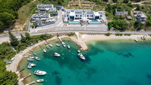An aerial view of a coastal property with modern buildings, a marina with boats, and clear turquoise waters. - Beachfront Villa Cordelia with Pool (Omiš)