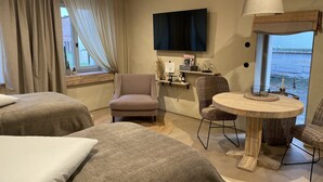 A hotel room with two beds, a sofa, a dining table, a TV, and a window with curtains. - Unterkunft Nähe Magdeburg und Oschersleben Motorpark (Wanzleben-Börde)