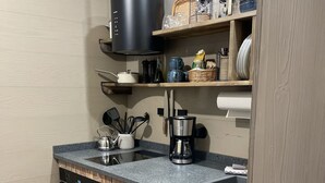 A kitchen with wooden cabinets, a granite countertop, a built-in oven, a coffee maker, and various kitchen utensils. - Unterkunft Nähe Magdeburg und Oschersleben Motorpark (Wanzleben-Börde)