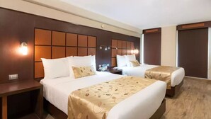 A hotel room with two beds, a wooden headboard, bedside lamps, and a nightstand.