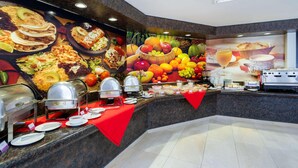 A buffet area with various food items and a large fruit display.