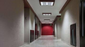 A corridor with a red carpet, recessed lighting, and a door on the right.
