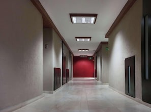 A corridor with a red carpet, recessed lighting, and a door on the right.