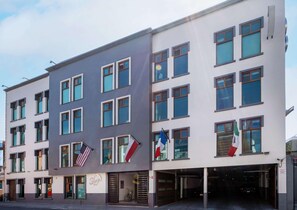 A multi-story hotel with a modern design, featuring a central entrance, multiple windows, and flags. - Sleep Inn Puebla Centro Historico (Puebla)
