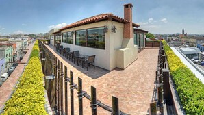 A rooftop terrace with a dining area, a brick chimney, and a view of the cityscape.
