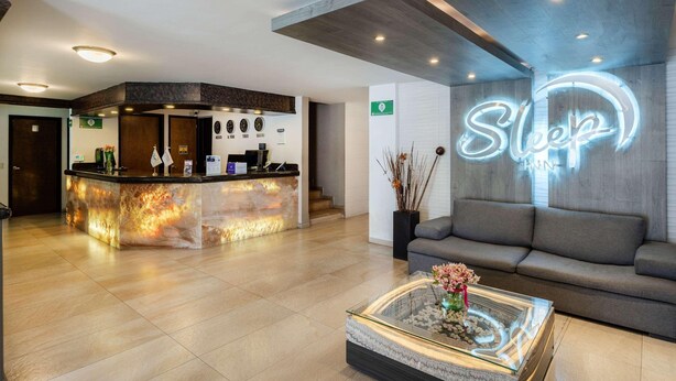 A hotel lobby with a reception desk, a sofa, and a neon sign.