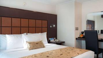 A hotel room with a bed, a desk, a chair, a telephone, and a mirror.