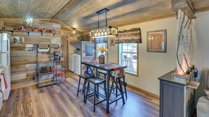 A rustic kitchen with wooden floors, a central island with stools, and a hanging light fixture.