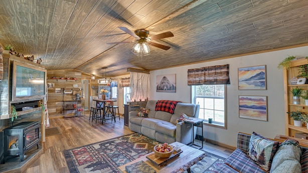 A cozy living room with a fireplace, a sofa, a coffee table, and a ceiling fan.
