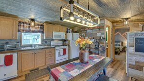 A modern kitchen with wooden cabinets, a central island, and a farmhouse-style ceiling.