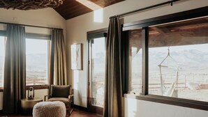 Ein Zimmer mit großem Fenster, Holzboden, gepolstertem Sitz und einer Pendelleuchte.