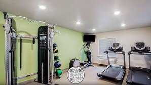 A gym with exercise equipment, treadmills, and a wall-mounted TV. - Woodspring Suites Downers Grove - Chicago (Downers Grove)