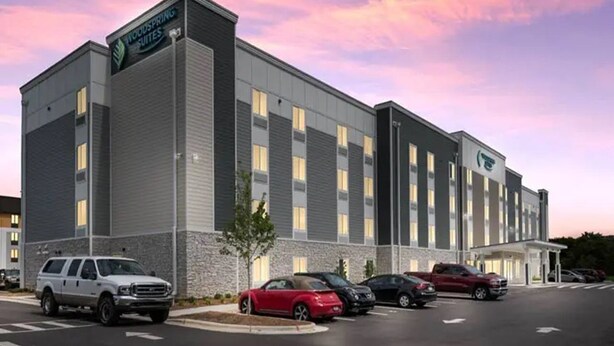 A modern hotel with a flat roof, a parking lot, and a clear sky. - Woodspring Suites Downers Grove - Chicago (Downers Grove)