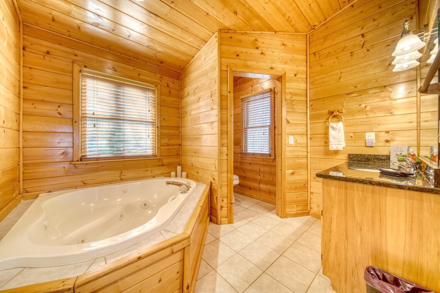 A wooden cabin bathroom with a large bathtub, a sink, and a toilet.