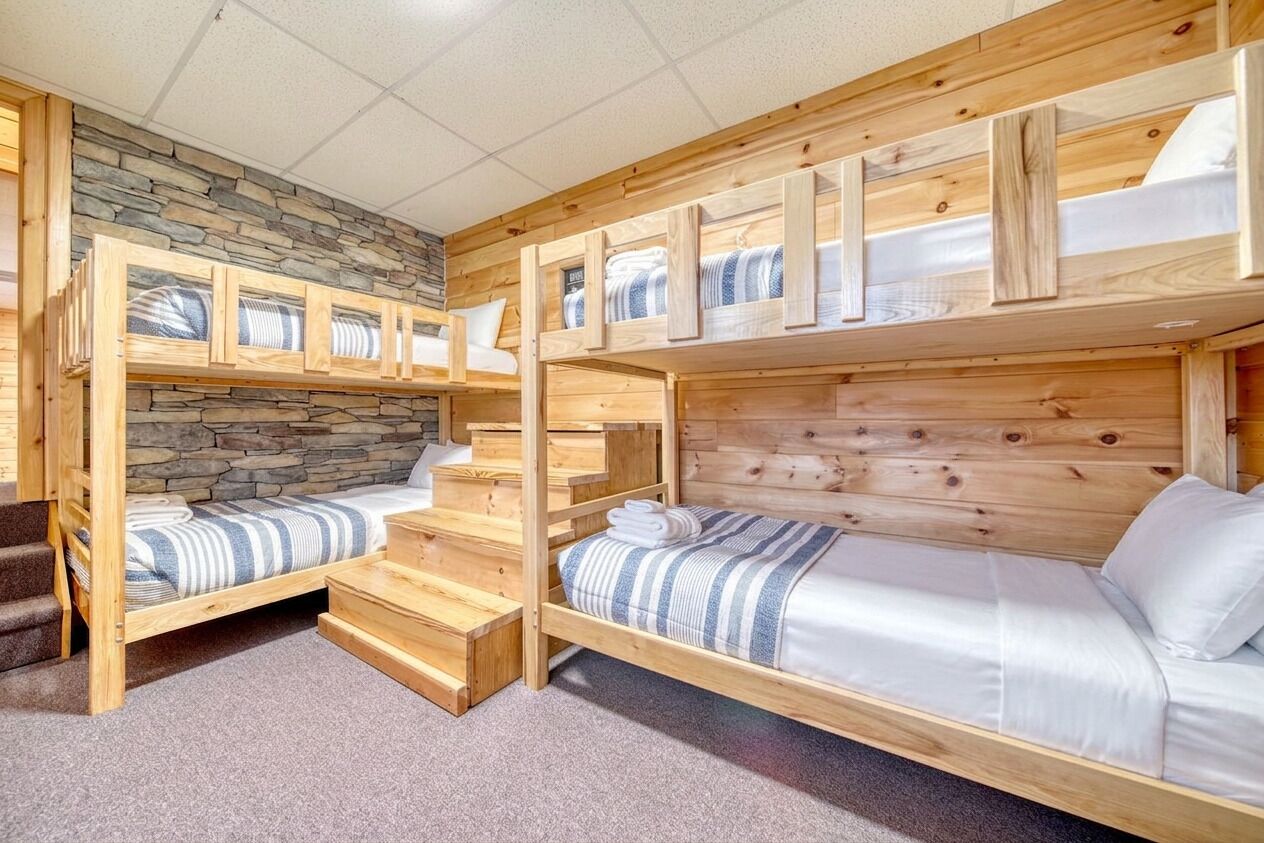 A bunk bed room with a stone wall and wooden headboard.