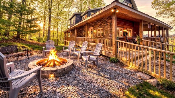 A cabin with a stone exterior, a fire pit, and outdoor seating. -  Cozy Cabin with Hot Tub in Blue Ridge Mountains (Morganton)