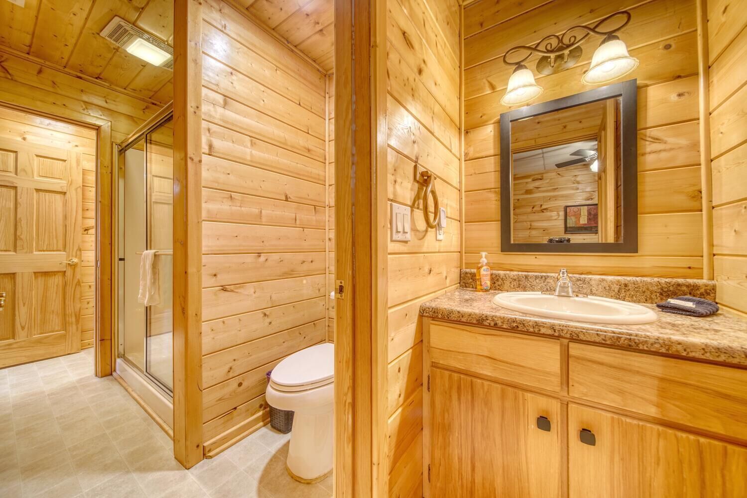 A wooden cabin bathroom with a sink, toilet, and shower.