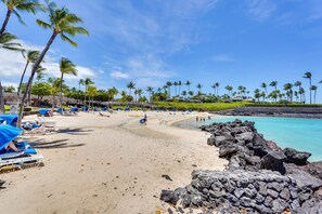 A beach with lounge chairs and umbrellas, a rocky shoreline, and palm trees. - KaMilo at Mauna Lani Condo w/ Resort Pool Access! (Waimea)