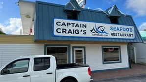 A restaurant named Captain Craig's Seafood Restaurant with a blue and white exterior and a signboard.