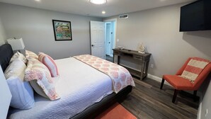 A bedroom with a bed, a desk, a chair, and a door.