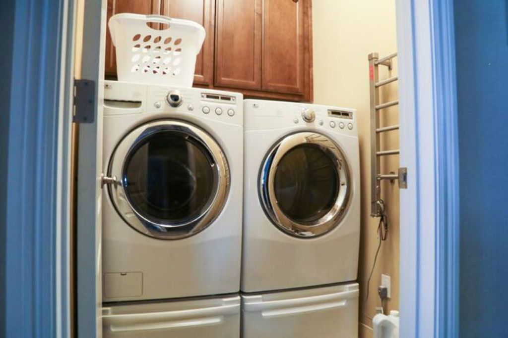 A laundry area with two front-loading washing machines and a drying rack.