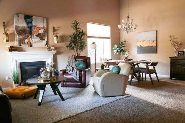 Un salon avec une cheminée, une table à manger et un lustre.