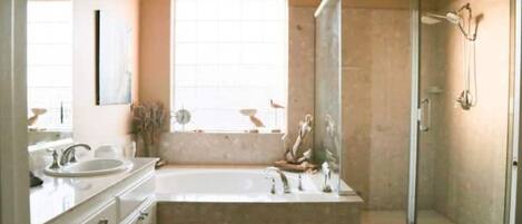 Un baño moderno con una bañera grande, zona de ducha separada y ventana que proporciona luz natural.