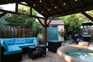 Une terrasse couverte avec un canapé bleu, une petite table et un jacuzzi.