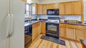 A kitchen with wooden cabinets, a microwave, a stove, and a dishwasher.