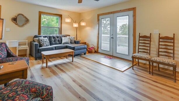 A living room with a sofa, coffee table, and chairs, a ceiling fan, and a large window.