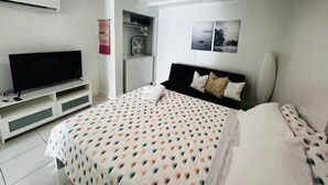 A bedroom with a bed, a TV on a stand, a wardrobe, and a wall-mounted air conditioner. - Modern Cozy Apartment in Hialeah Miami Int Airport (Hialeah)