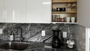 A kitchen with a granite countertop, a coffee maker, and a sink. - Spacious Apartment Central Located (Hialeah)